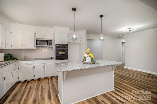 kitchen with decorative backsplash, a kitchen island, wood finished floors, black appliances, and white cabinetry