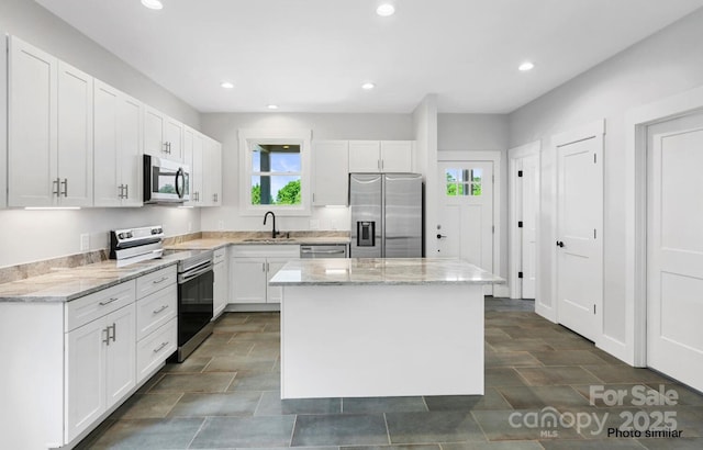 kitchen with white cabinetry, a kitchen island, appliances with stainless steel finishes, and a sink