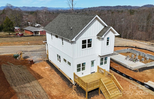 back of property with a shingled roof, a mountain view, and board and batten siding