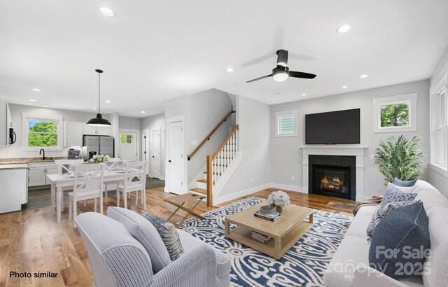 living room with stairs, light wood finished floors, and a healthy amount of sunlight