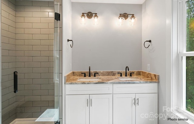 bathroom with a sink, a shower stall, and double vanity