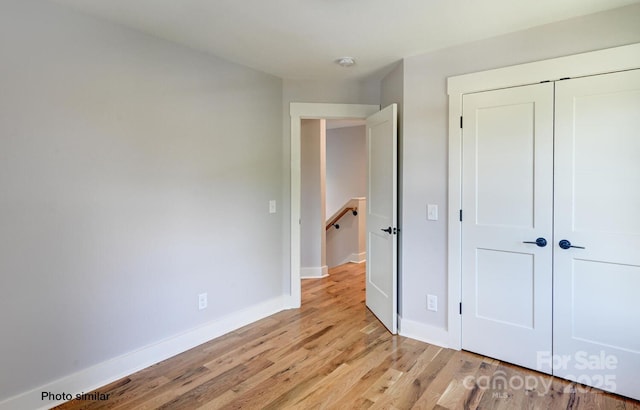 unfurnished bedroom featuring a closet, light wood-style flooring, and baseboards