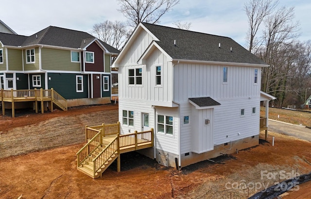 rear view of house with stairs, board and batten siding, and roof with shingles