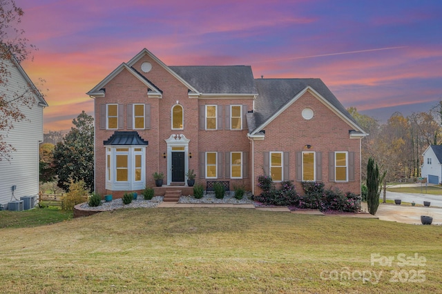 view of front of home with brick siding and a lawn