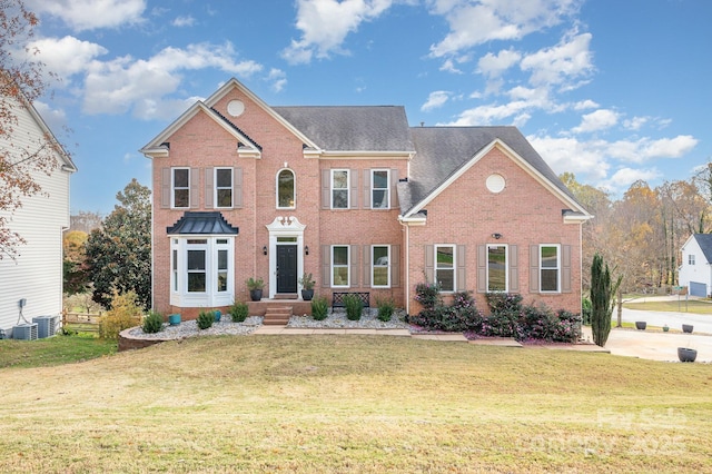 colonial home with a front lawn and brick siding