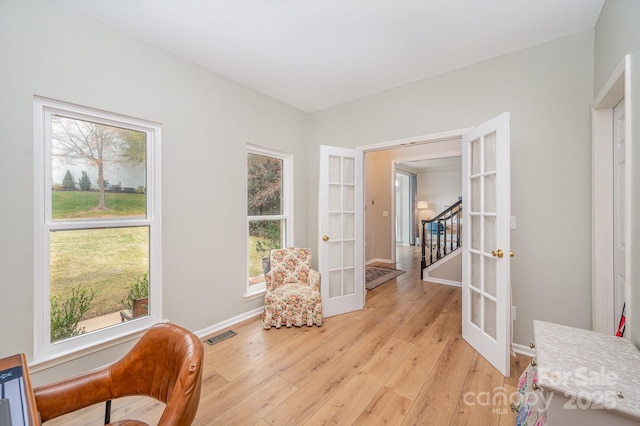 sitting room with light wood-style flooring, visible vents, baseboards, french doors, and stairway