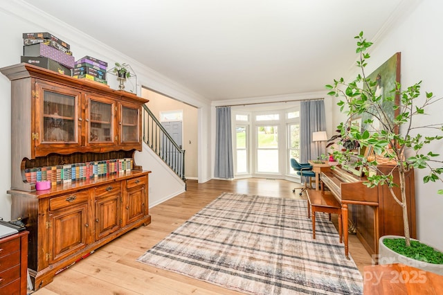 entryway with light wood-style flooring, stairs, and ornamental molding