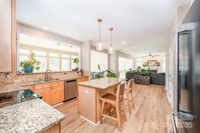 kitchen featuring open floor plan, a center island, fridge with ice dispenser, stainless steel dishwasher, and a sink