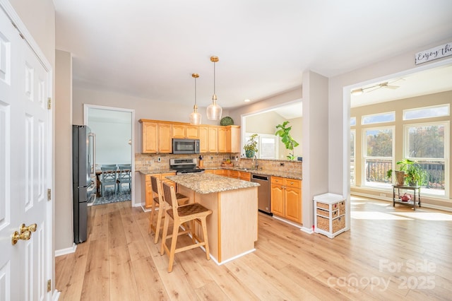 kitchen with light wood-style floors, tasteful backsplash, stainless steel appliances, and a center island