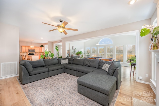 living room featuring light wood finished floors, a fireplace, visible vents, and baseboards