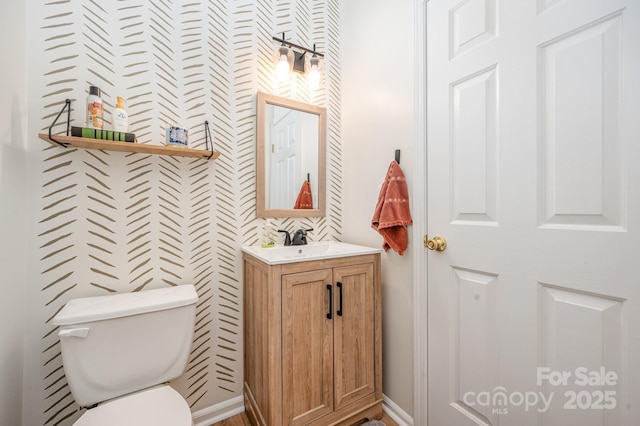 bathroom with vanity, toilet, and baseboards