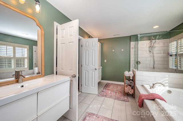 full bathroom with a garden tub, vanity, baseboards, and tiled shower