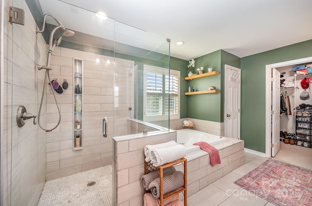 bathroom featuring a stall shower, a walk in closet, a bath, and tile patterned floors