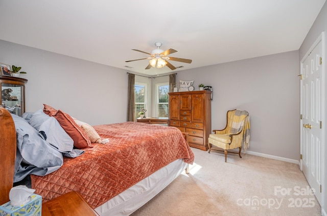 bedroom with a closet, light colored carpet, ceiling fan, and baseboards