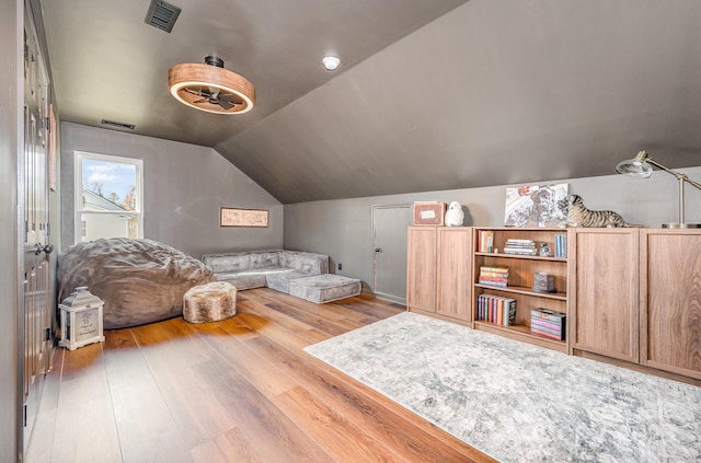 living area with lofted ceiling, wood-type flooring, and visible vents