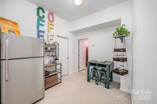 kitchen with baseboards, carpet flooring, and freestanding refrigerator