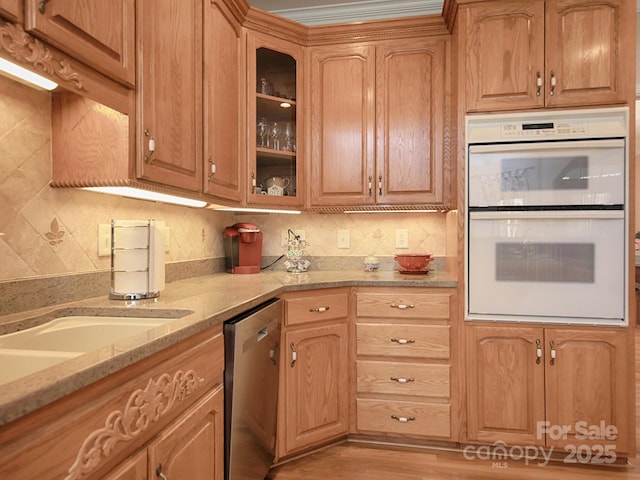 kitchen with double oven, light stone counters, stainless steel dishwasher, decorative backsplash, and glass insert cabinets