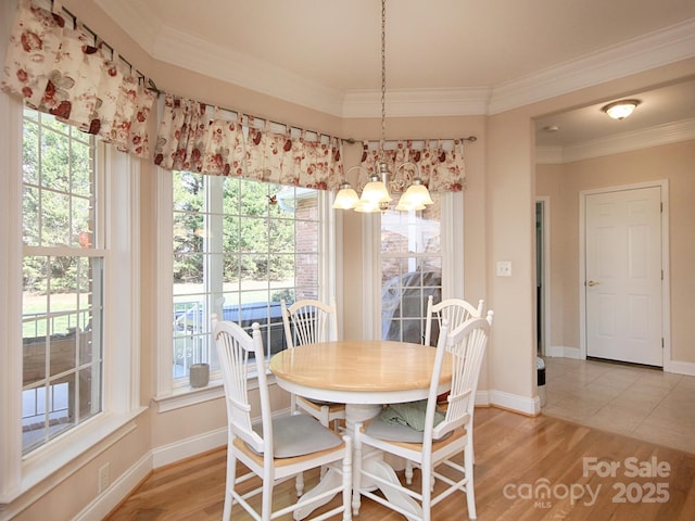 dining space featuring light wood finished floors, ornamental molding, a chandelier, and baseboards