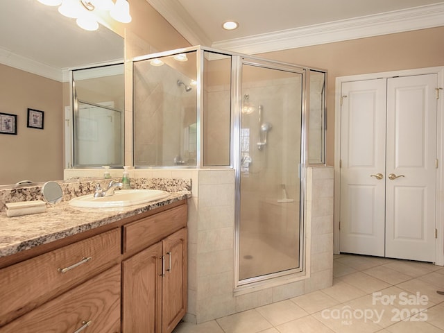 bathroom featuring tile patterned flooring, crown molding, a shower stall, and vanity