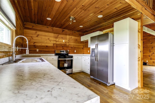 3640 Oak Haven Ln, Shelby, NC 28150 - kitchen with stainless steel appliances, a sink, wood walls, white cabinetry, and wood finished floors