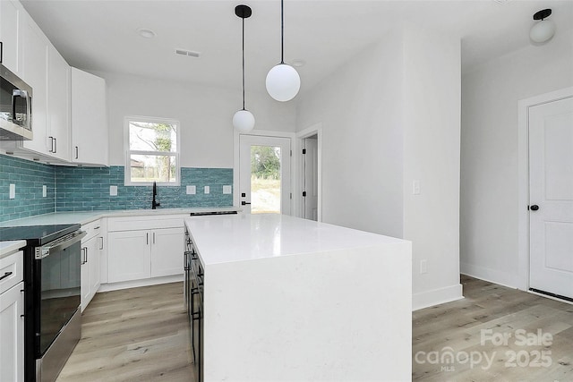 kitchen featuring backsplash, visible vents, range with electric cooktop, and light wood finished floors