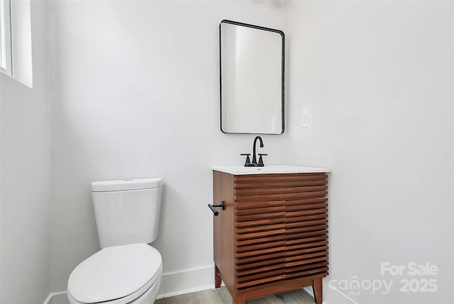 bathroom with toilet, vanity, and baseboards