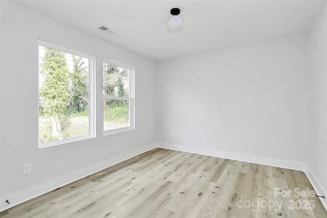 unfurnished room with baseboards, visible vents, and light wood finished floors