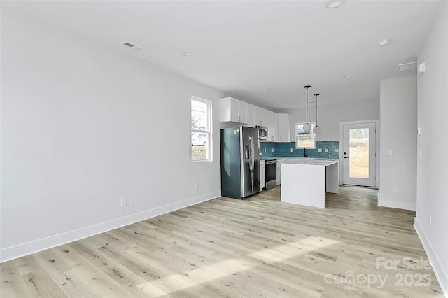 kitchen with light wood-style flooring, backsplash, appliances with stainless steel finishes, and light countertops