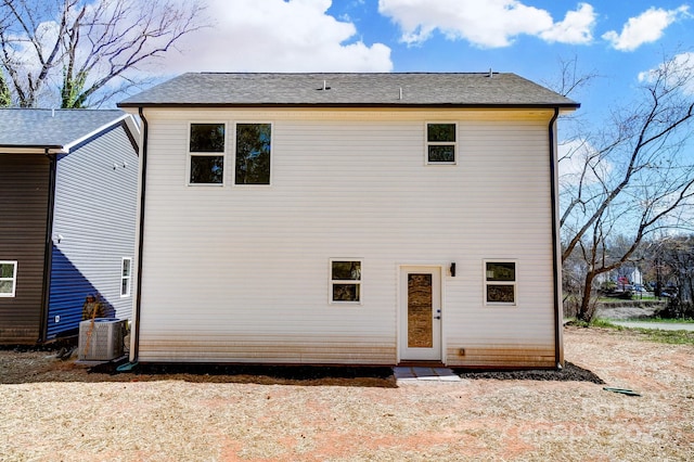 rear view of house featuring central air condition unit and a shingled roof