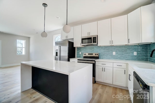 kitchen with a sink, a kitchen island, appliances with stainless steel finishes, light wood-style floors, and decorative backsplash