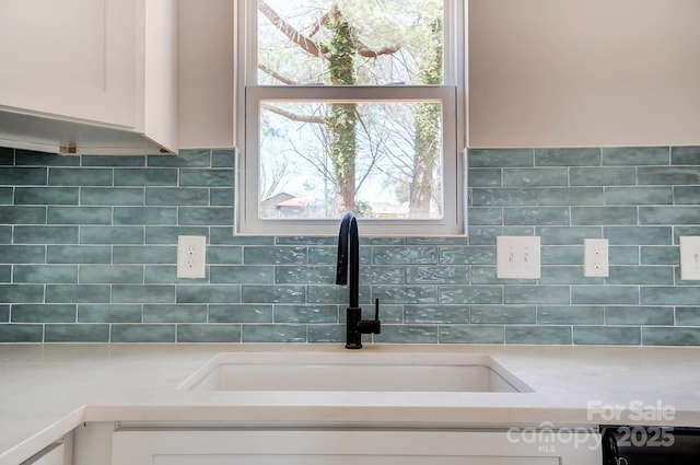 interior details featuring white cabinetry, light countertops, and a sink