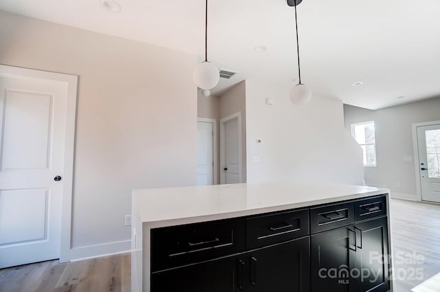 kitchen with light wood finished floors, visible vents, light countertops, and dark cabinetry