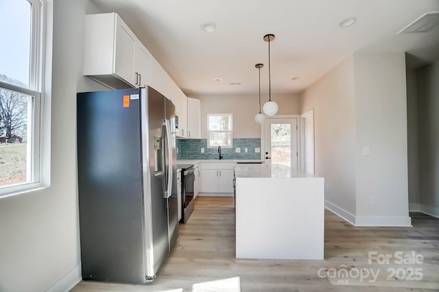 kitchen featuring a kitchen island, stainless steel fridge, tasteful backsplash, and light wood finished floors