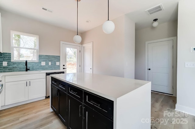 kitchen featuring stainless steel dishwasher, visible vents, light wood finished floors, and a sink