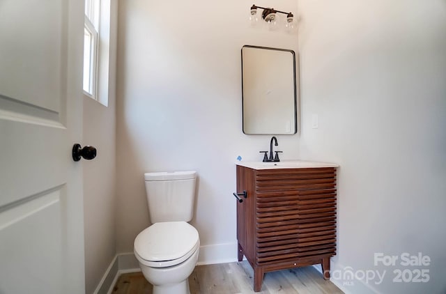 bathroom with baseboards, toilet, vanity, and wood finished floors