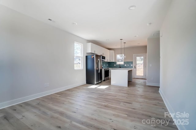 kitchen featuring light countertops, plenty of natural light, stainless steel appliances, backsplash, and white cabinets