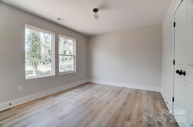 spare room featuring baseboards, light wood finished floors, and visible vents