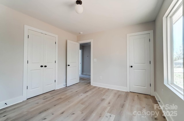 unfurnished bedroom with baseboards, a closet, and light wood-style flooring
