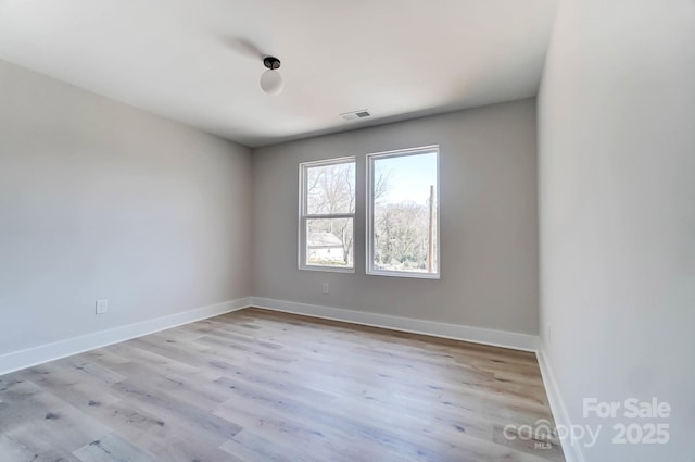 empty room with baseboards, visible vents, and wood finished floors