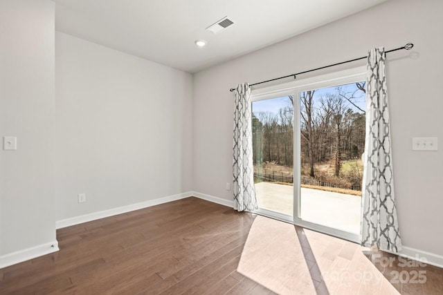 spare room featuring recessed lighting, wood finished floors, visible vents, and baseboards