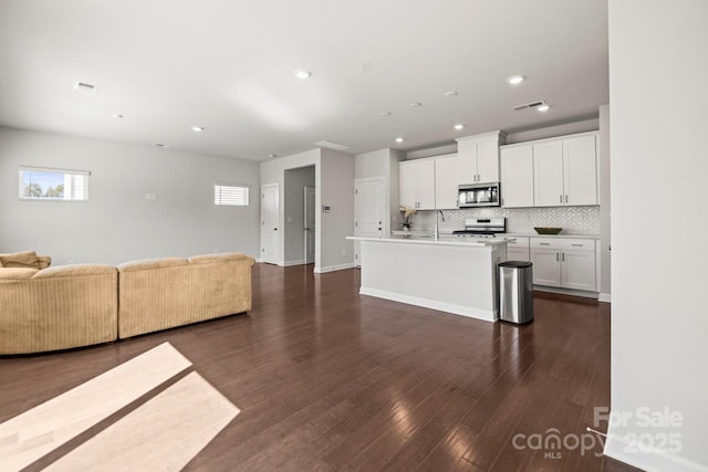 unfurnished living room with dark wood-type flooring, recessed lighting, visible vents, and baseboards