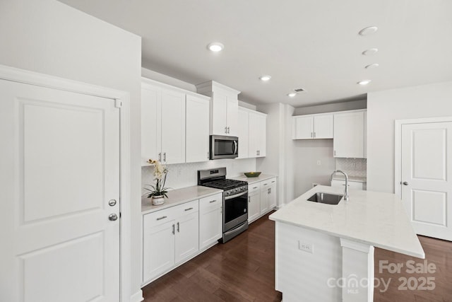 kitchen featuring dark wood finished floors, white cabinetry, stainless steel appliances, and a sink