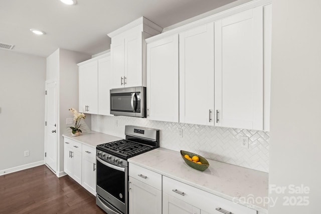 kitchen featuring stainless steel appliances, light stone counters, white cabinetry, and decorative backsplash