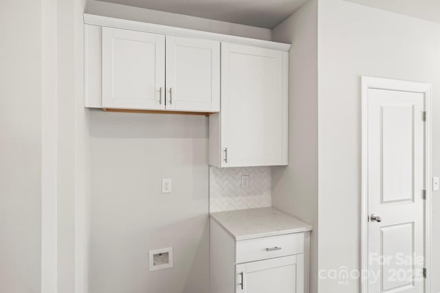 kitchen featuring tasteful backsplash, light stone counters, and white cabinets