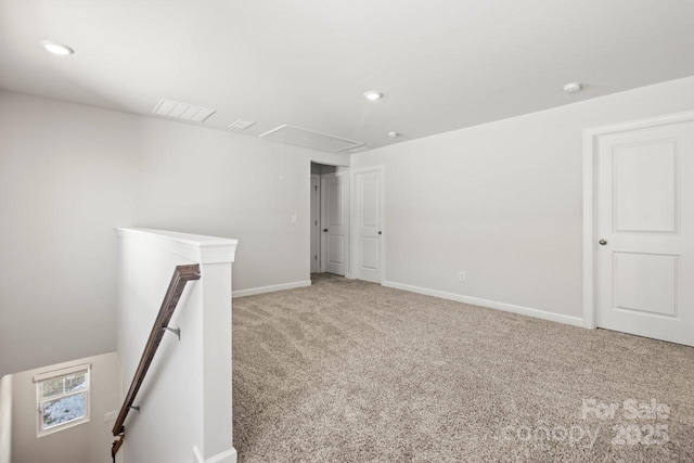 spare room featuring attic access, recessed lighting, light colored carpet, and baseboards