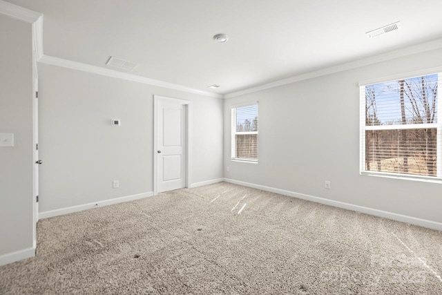 carpeted empty room with baseboards, visible vents, and crown molding