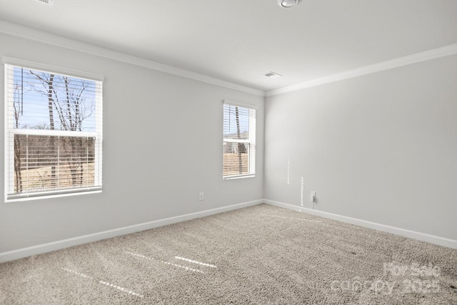 carpeted spare room with ornamental molding, visible vents, and baseboards