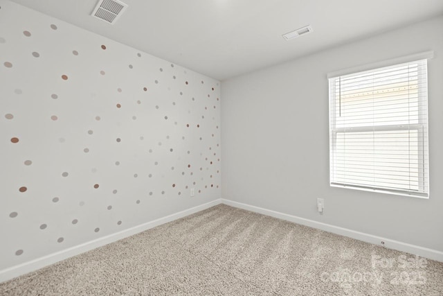 empty room featuring baseboards, visible vents, and light colored carpet