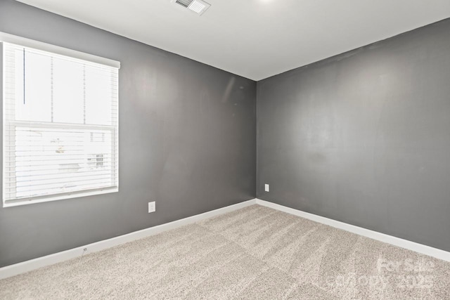 spare room featuring carpet flooring, visible vents, and baseboards