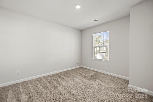 spare room with carpet flooring, visible vents, and baseboards